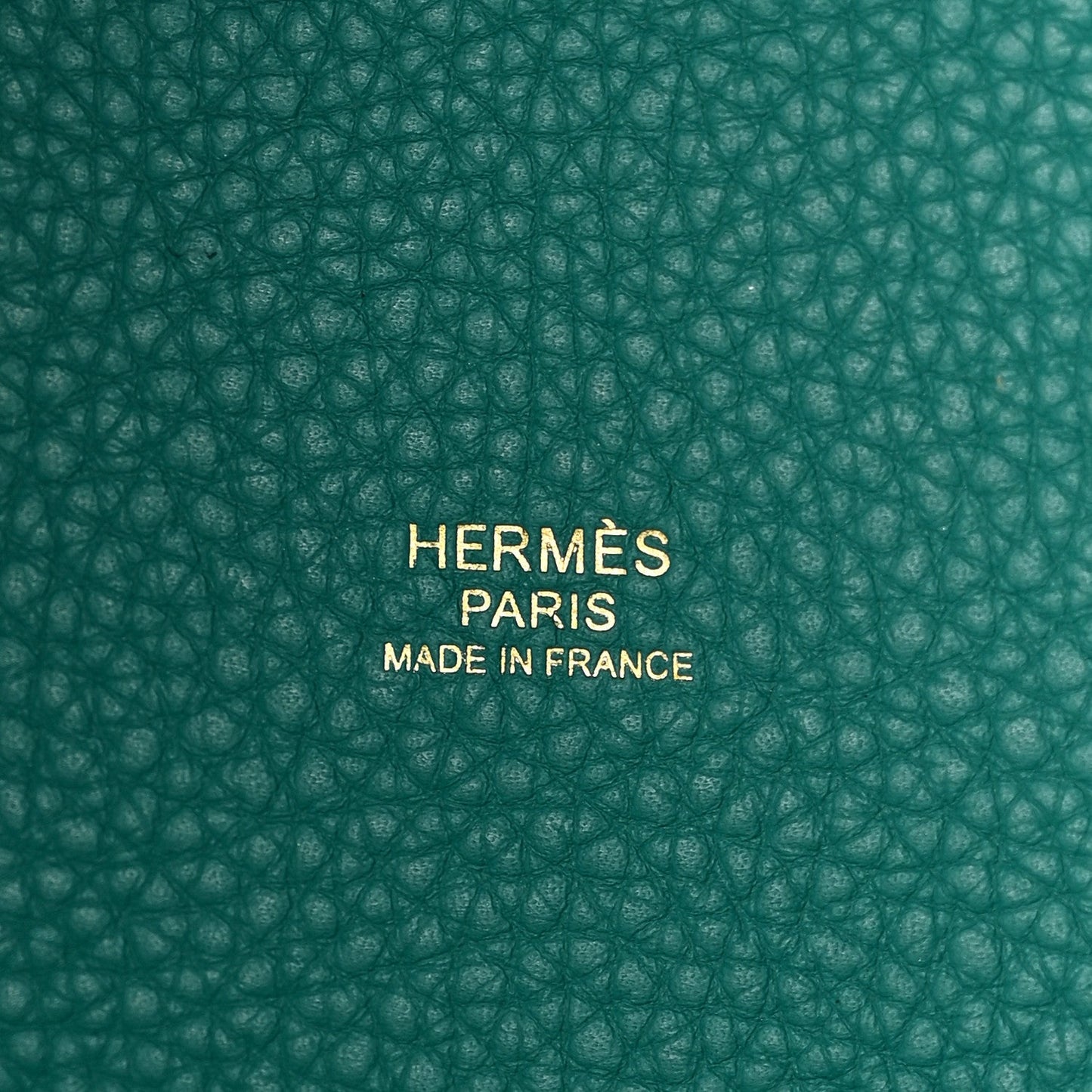 Close-up of green pebbled leather base with centered brand stamp