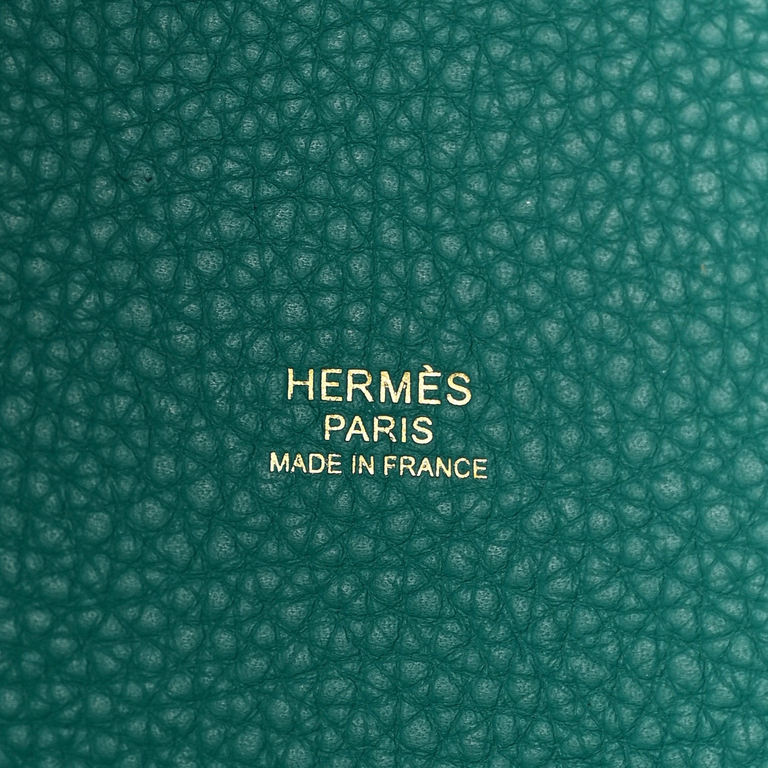 Close-up of green pebbled leather base with centered brand stamp
