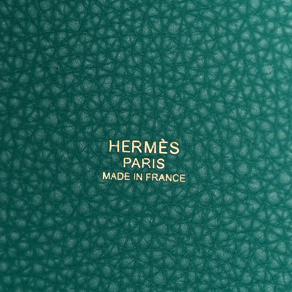 Close-up of green pebbled leather base with centered brand stamp