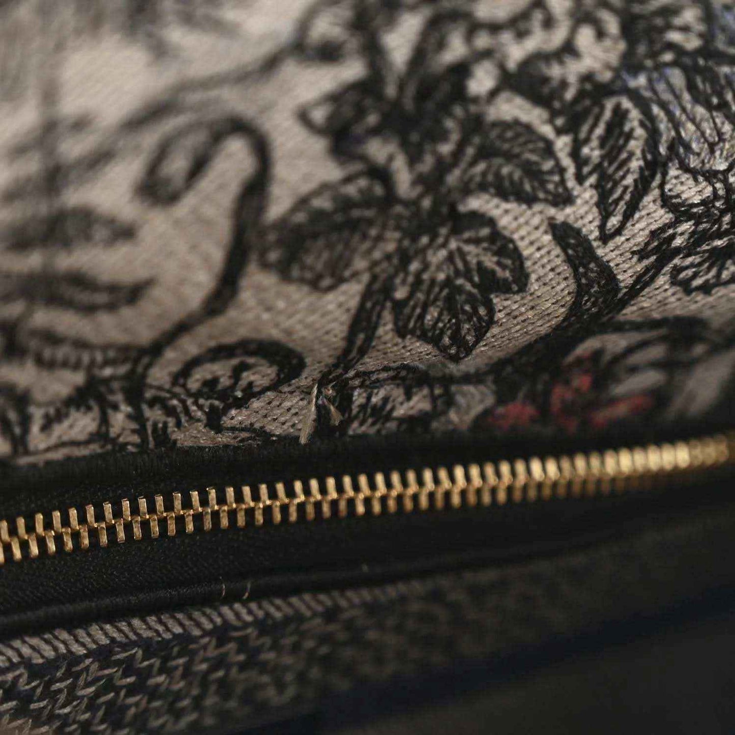 Embroidered denim bag with floral stitching and gold zipper