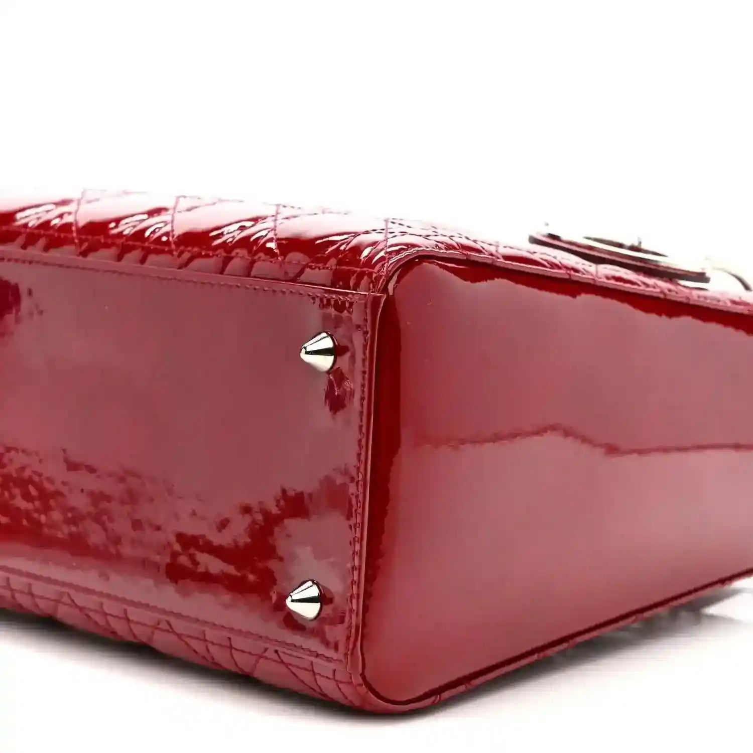 Red patent leather handbag side with silver studs and glossy finish.