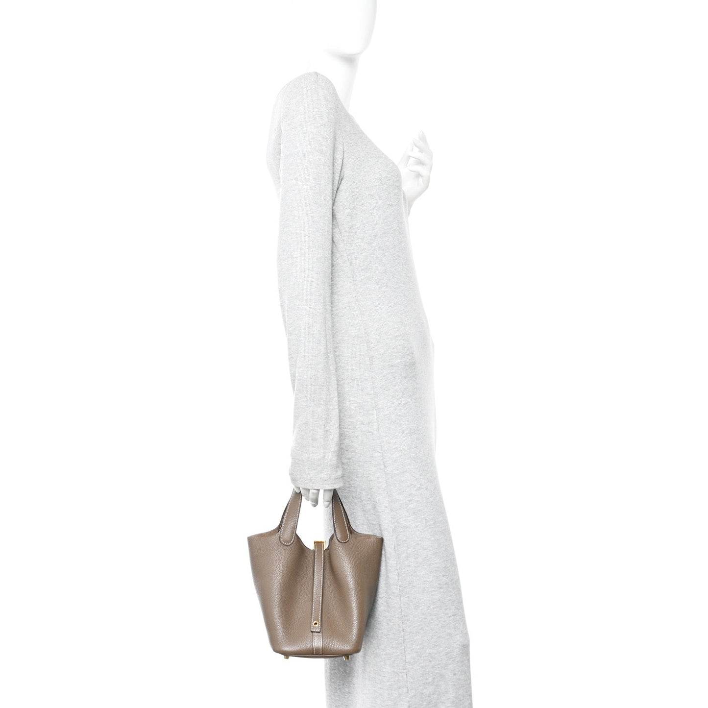 Taupe leather bucket bag held by a model with long sleeves.