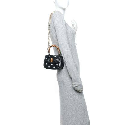 Gucci mini top handle bag, black embossed lizard texture, gold chain strap on model