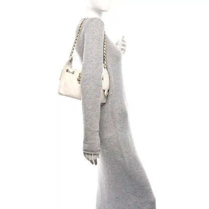 White quilted mini handbag side profile with gold chain strap and flap detail.