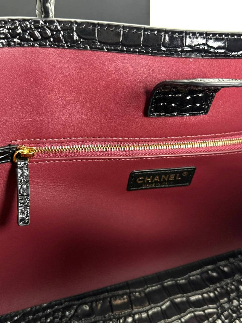 Close-up of burgundy interior lining with black croc-embossed trim and gold zipper pull