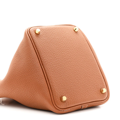 Tan leather bucket bag with gold-tone studs at corners and triangular shape