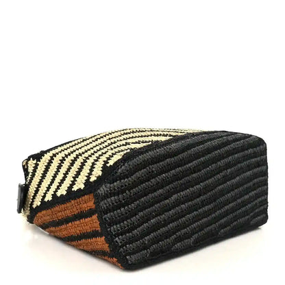 Small raffia puzzle bag side view with black textured leather panel and striped weave
