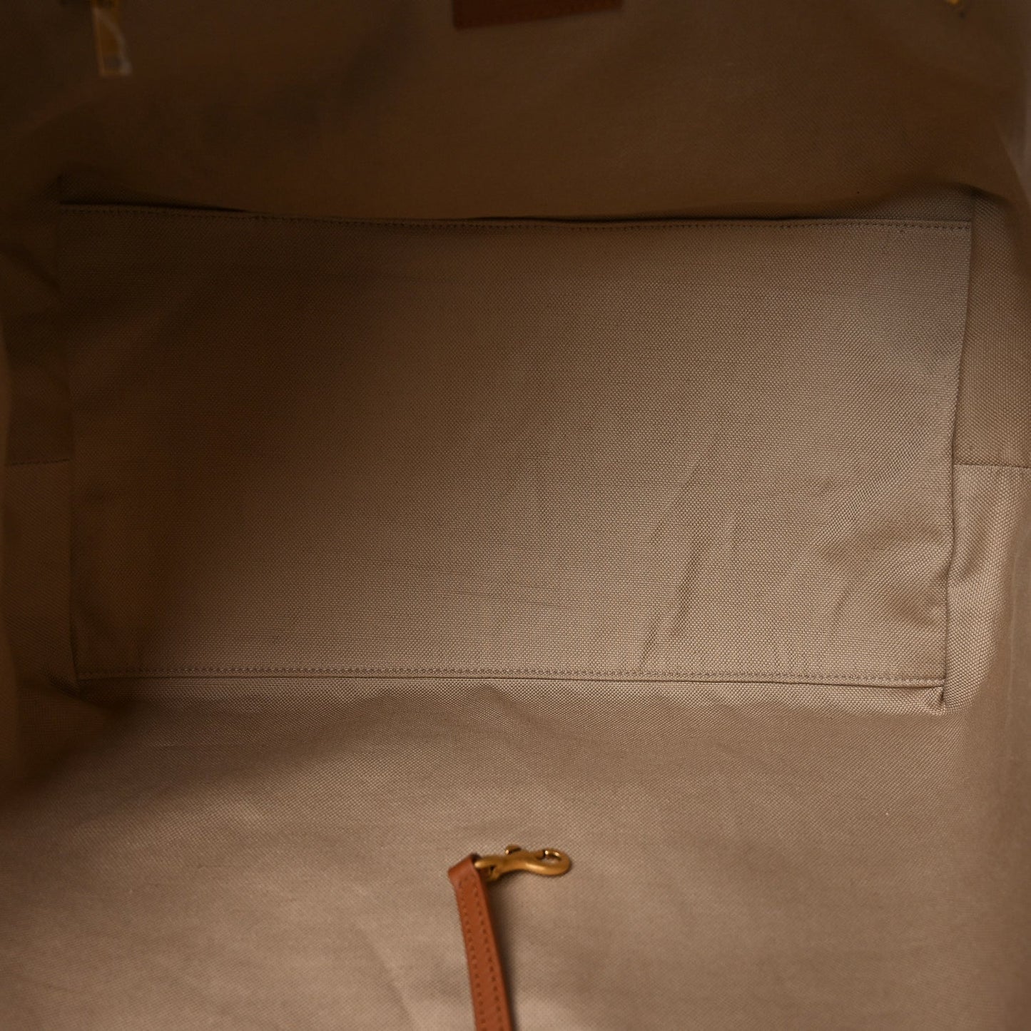 Tote bag interior with beige lining, stitched pocket seam and leather pull tab