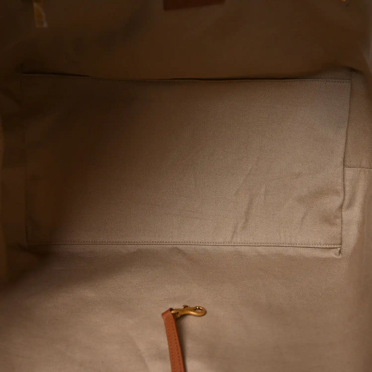 Tote bag interior with beige lining, stitched pocket seam and leather pull tab