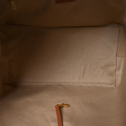Tote bag interior with beige lining, stitched pocket seam and leather pull tab