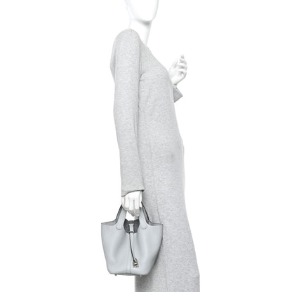 Light blue pebbled leather bucket tote bag worn by person with top handles