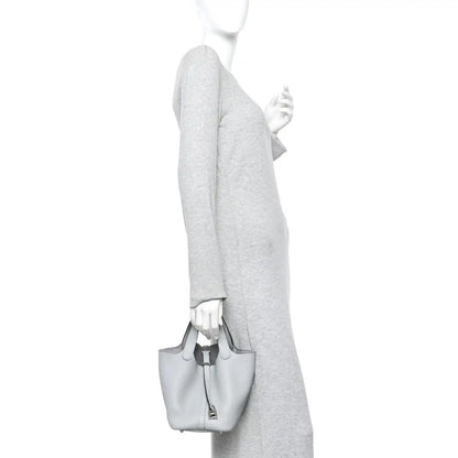 Light blue pebbled leather bucket tote bag worn by person with top handles
