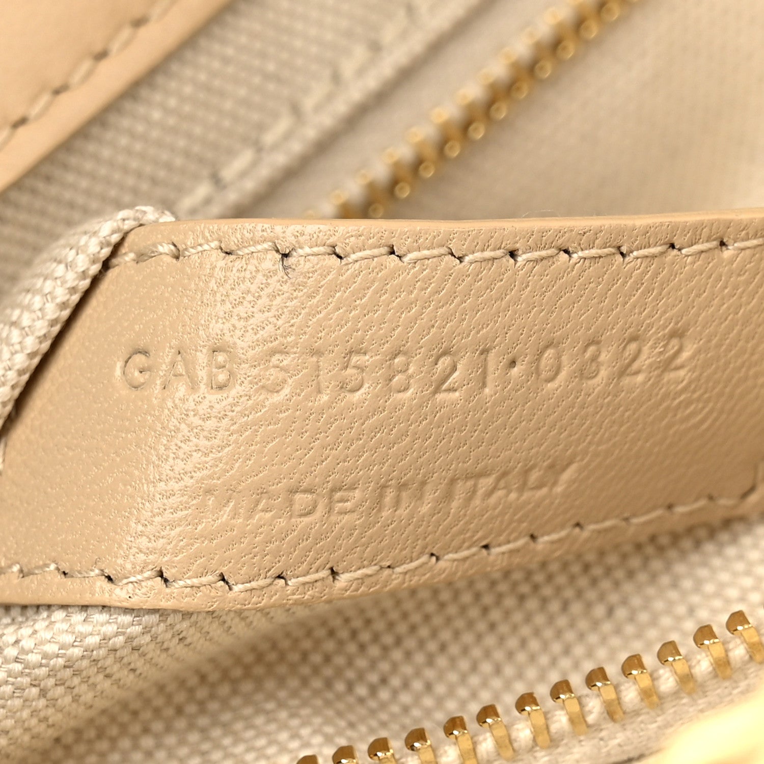 Beige leather strap end with embossed code and stitched trim