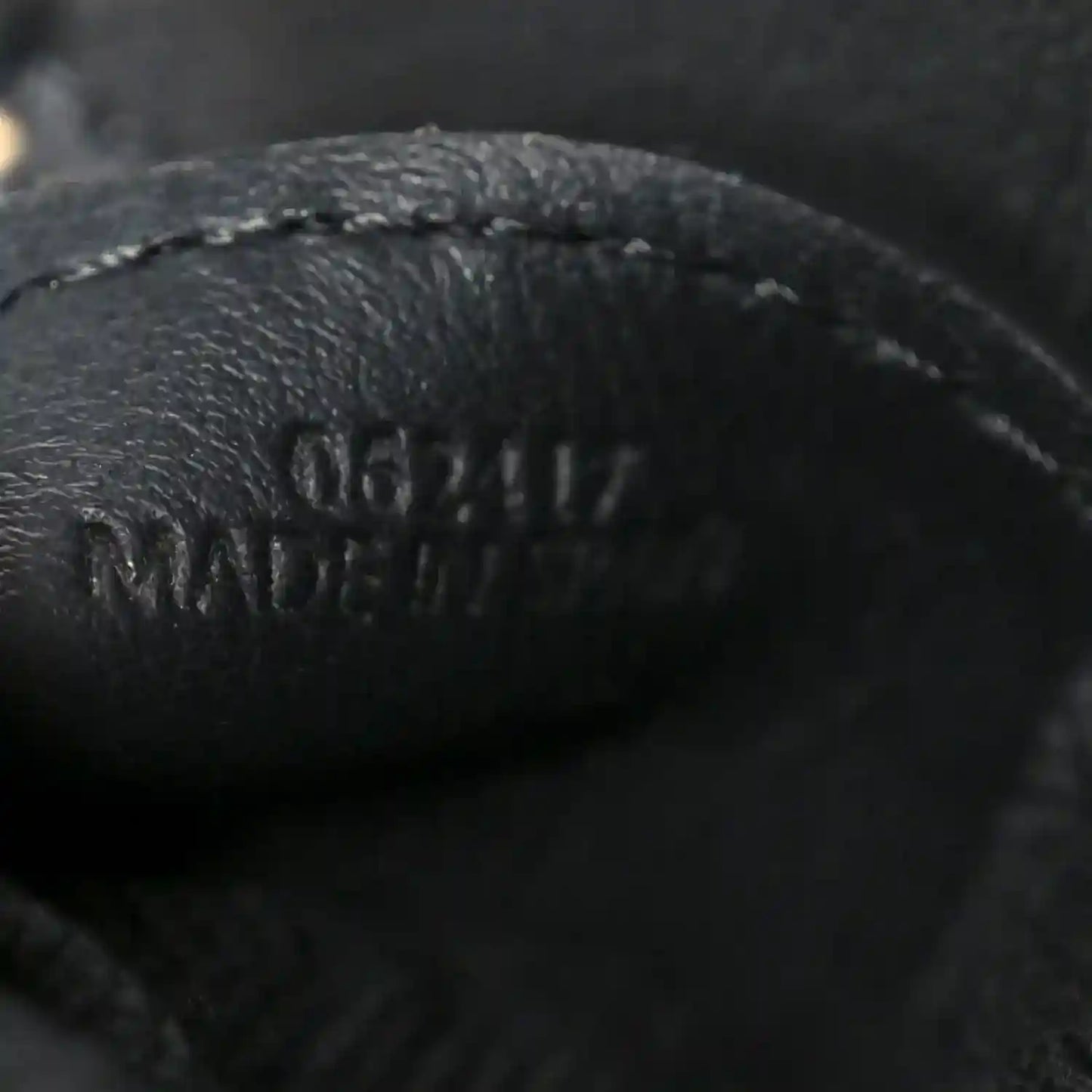 Close-up of black leather logo on small raffia puzzle bag