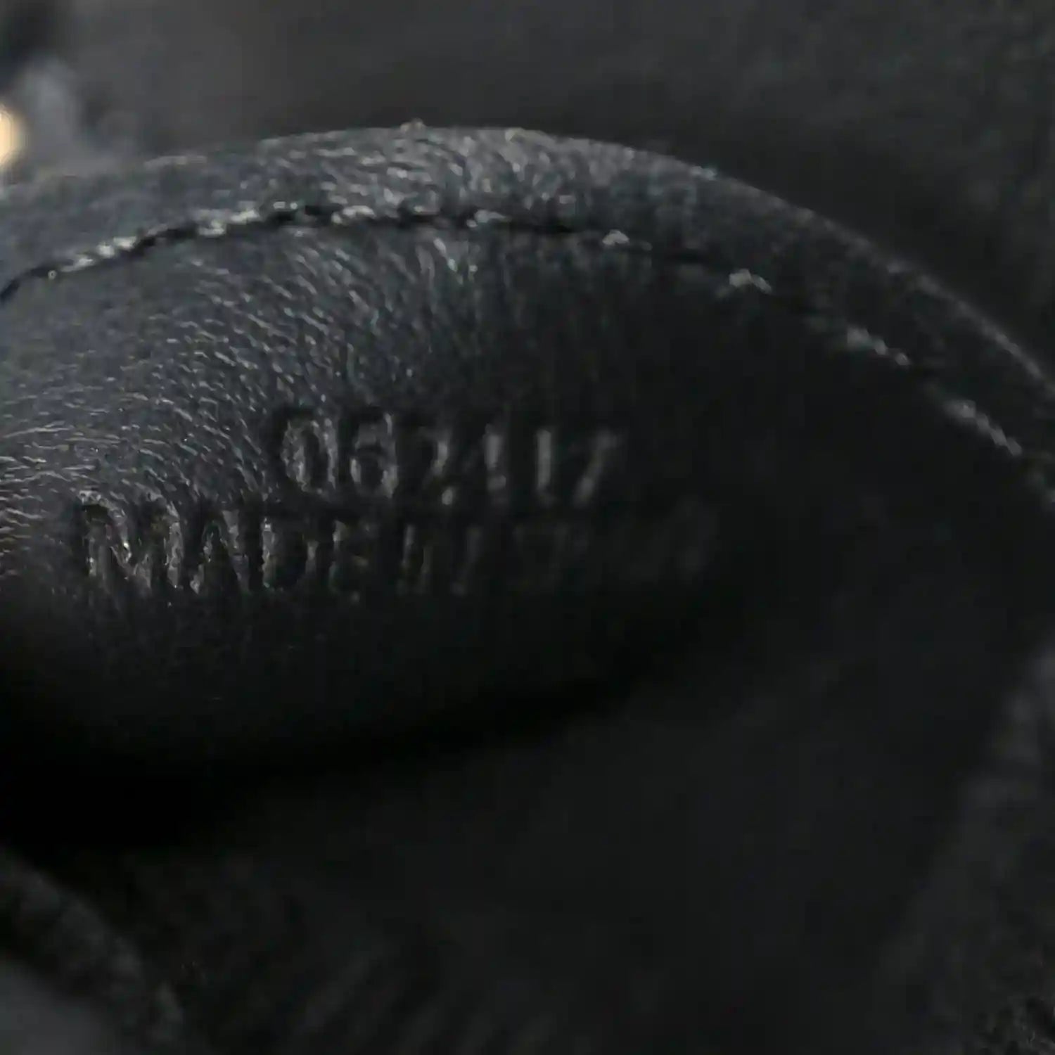 Close-up of black leather logo on small raffia puzzle bag