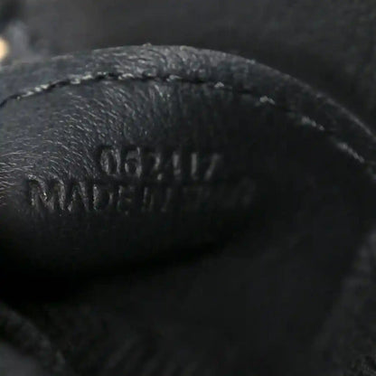 Close-up of black leather logo on small raffia puzzle bag
