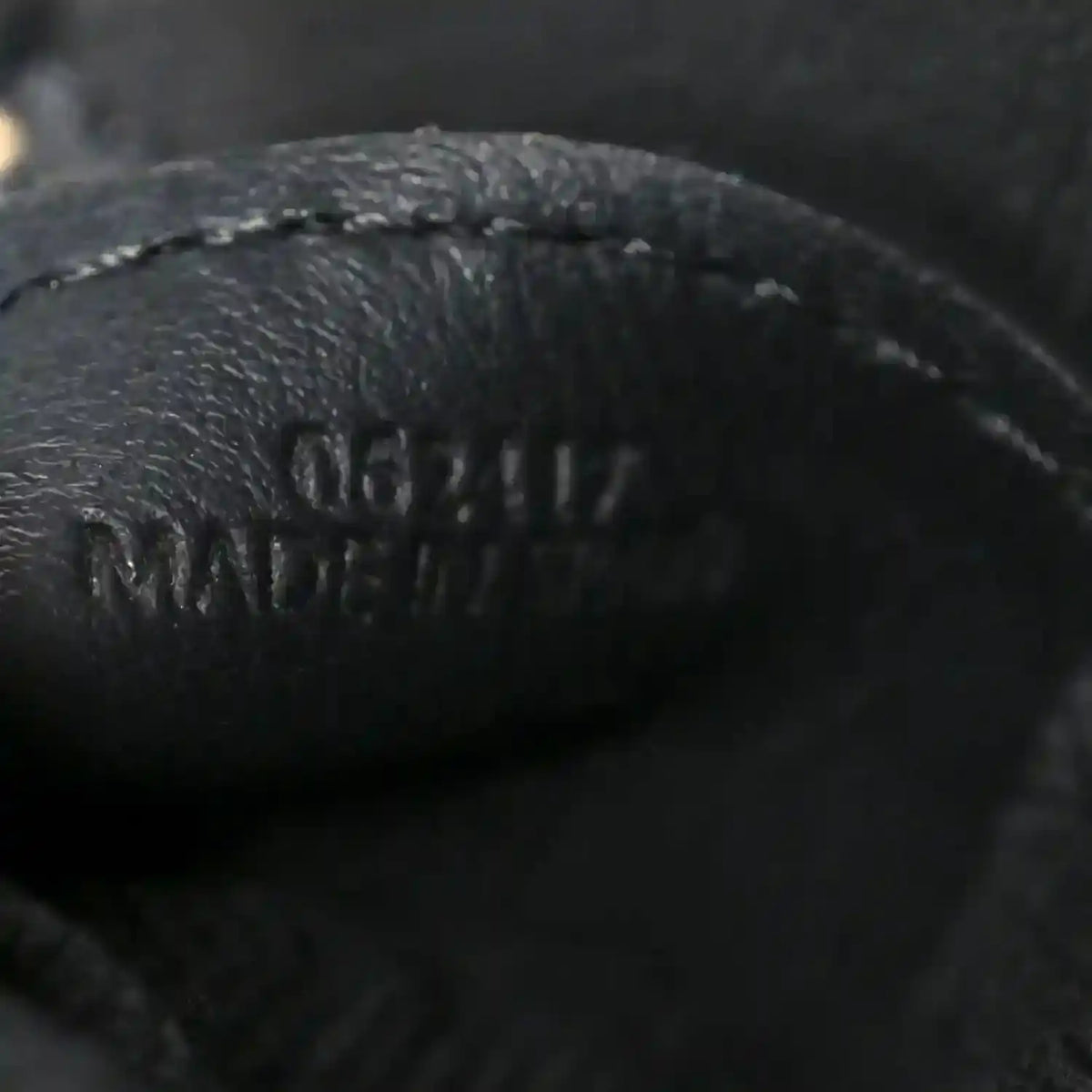 Close-up of black leather logo on small raffia puzzle bag