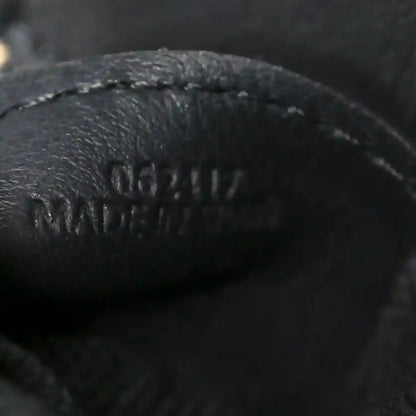 Close-up of black leather logo on small raffia puzzle bag