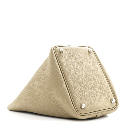 Beige leather handbag with triangular fold, corner snaps, and metal studs
