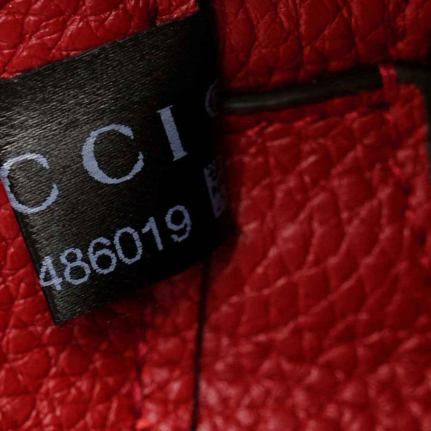Red leather bag tag with Gucci and style code printed on fabric label