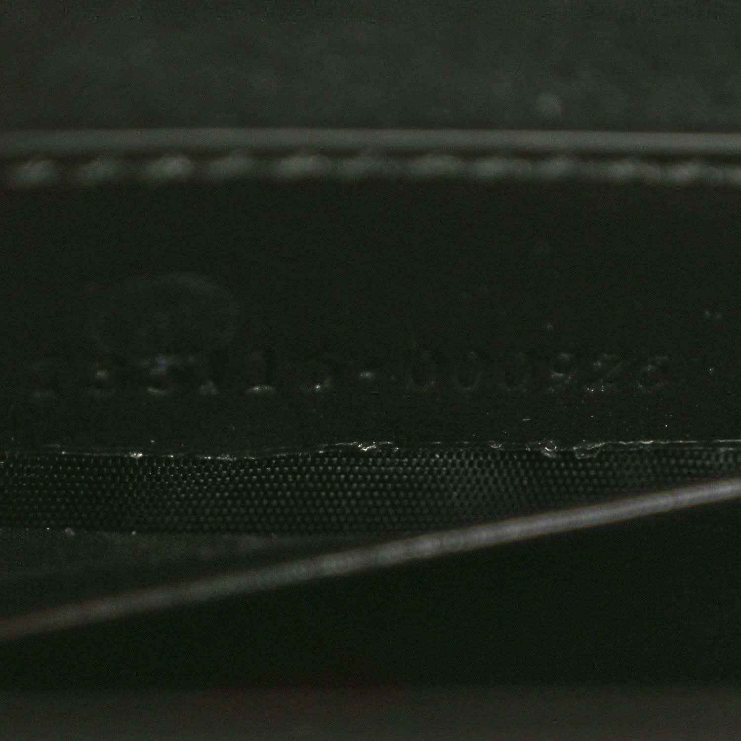 Black handbag close-up of textured leather panel and stitched edge.