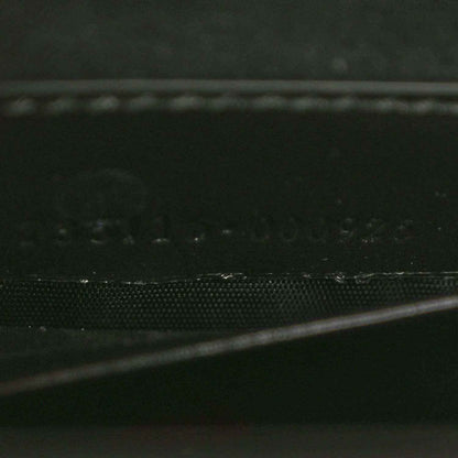 Black handbag close-up of textured leather panel and stitched edge.