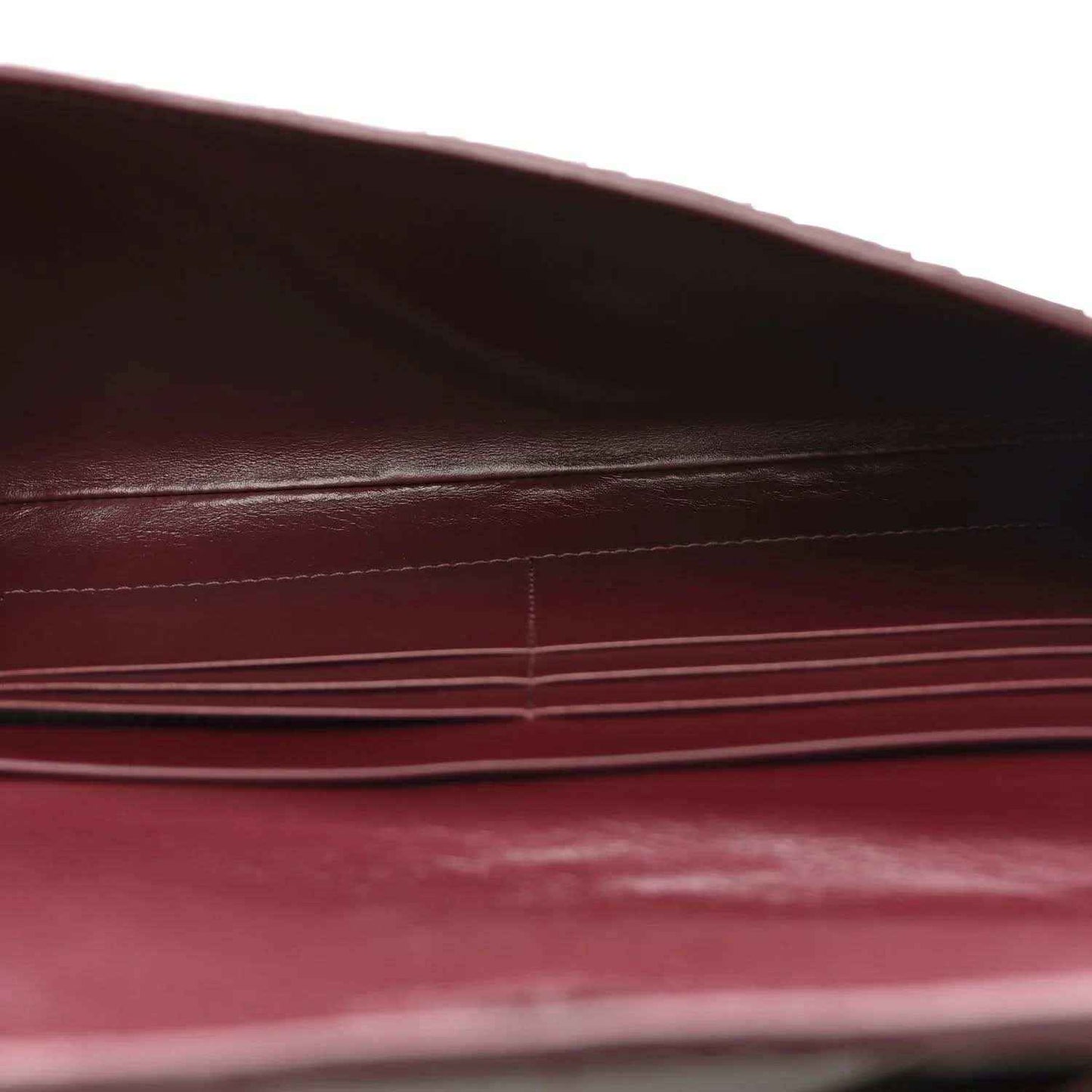 Burgundy leather clutch close-up showing interior seams and stitched detailing