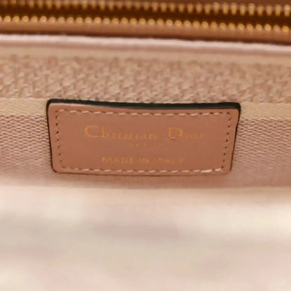 Rose-pink handbag leather brand patch with gold stitching and embossed text