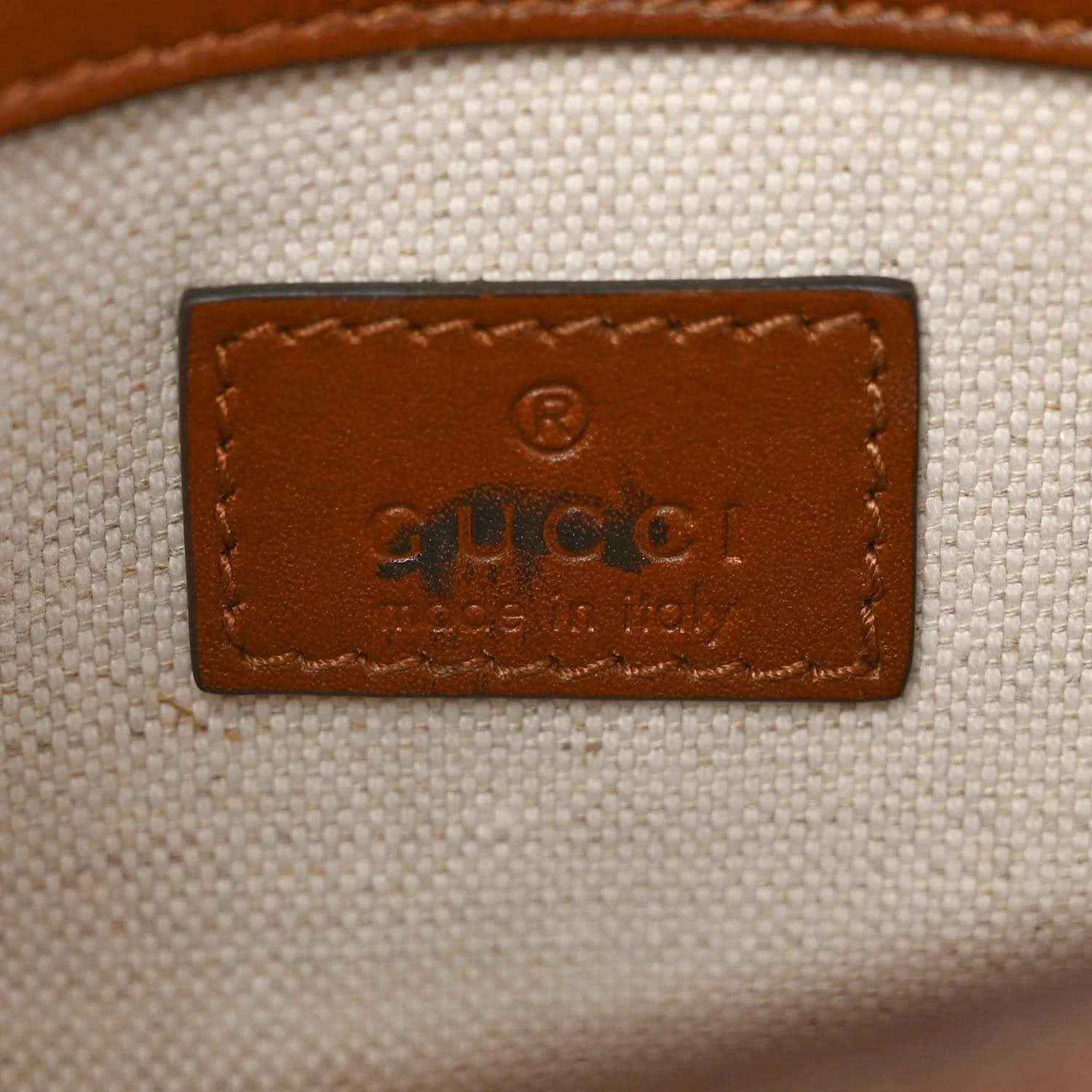 Mini bag leather patch with embossed logo on light canvas background