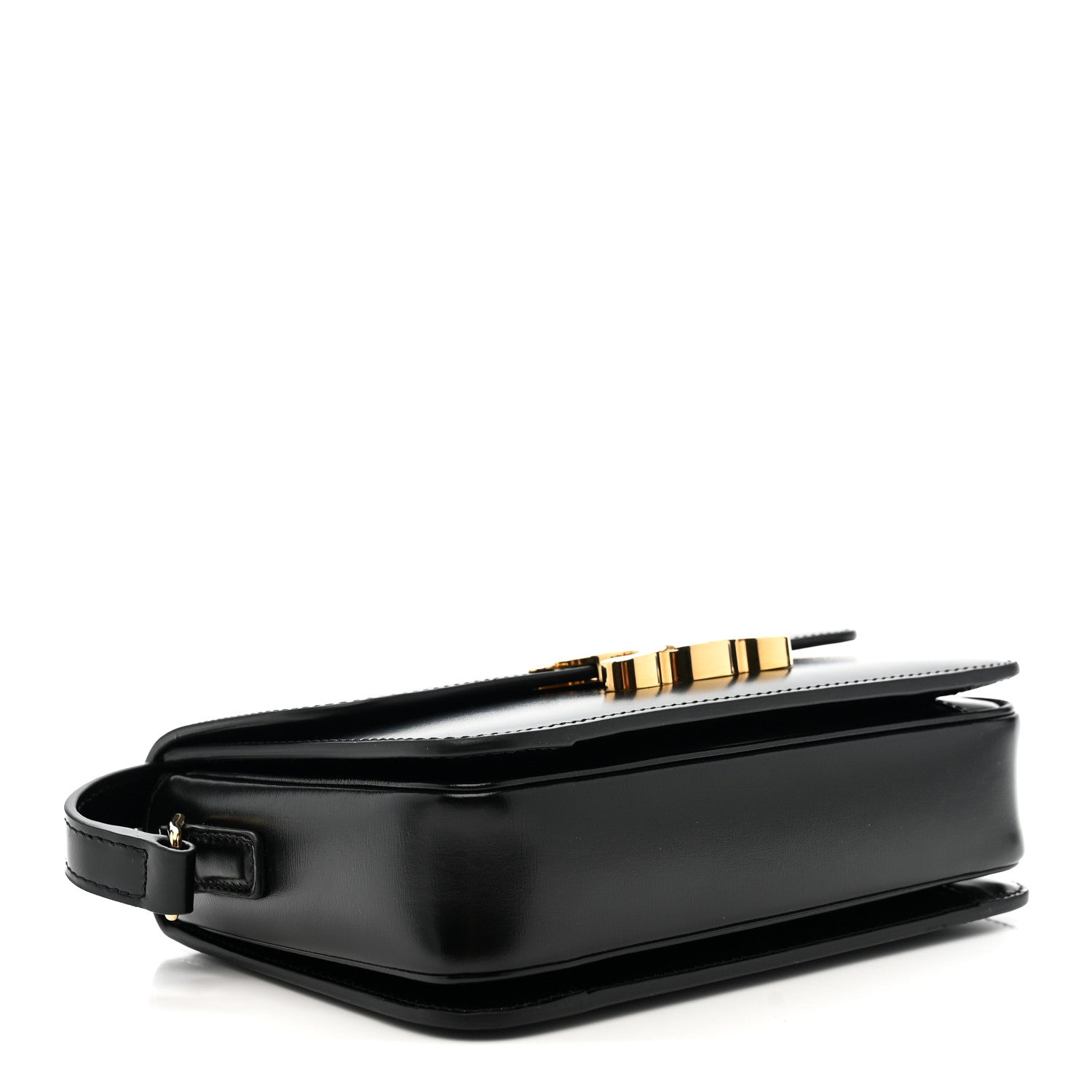 Black leather crossbody bag with gold buckle and structured base, side view.