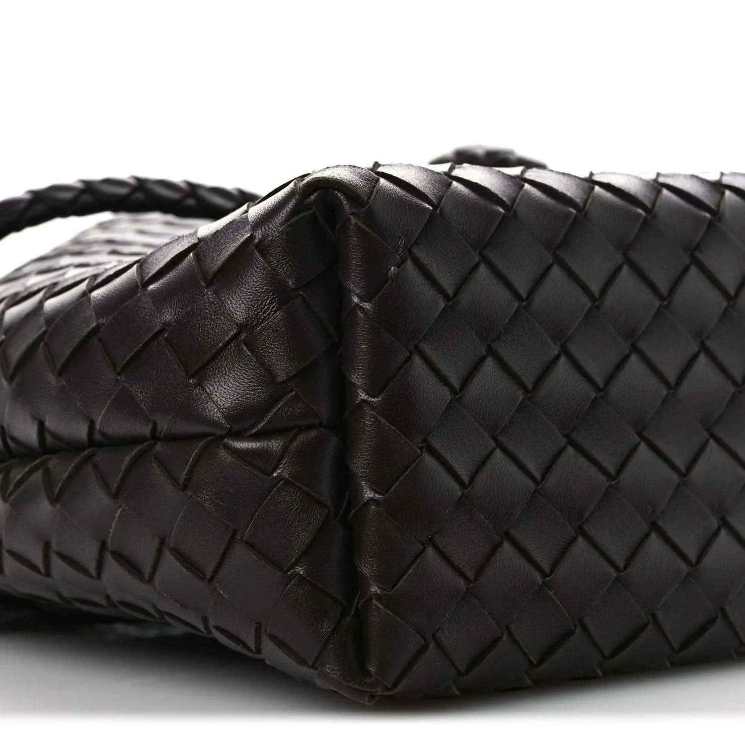 Small intrecciato nappa leather bucket bag close-up, dark color, woven texture and fold