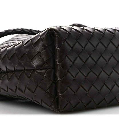 Small intrecciato nappa leather bucket bag close-up, dark color, woven texture and fold