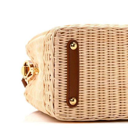 Tan rattan handbag side with brown leather trim and two gold snap buttons