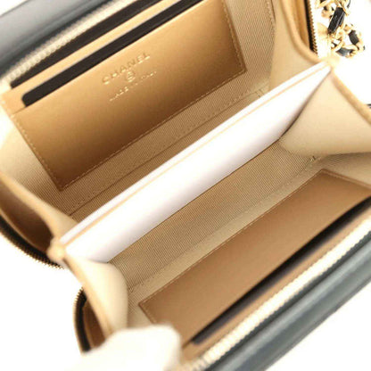 Beige fabric interior of black quilted Chanel clutch with zipper opening