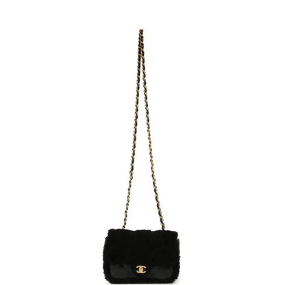 Black mini flap bag with shearling and gold chain strap, quilted flap and CC clasp