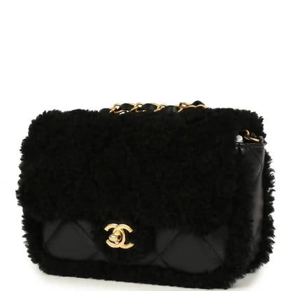 Black mini flap bag with shearling, quilted front and gold CC logo, chain strap