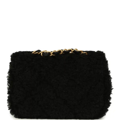 Black mini flap bag in shearling with gold chain top detail