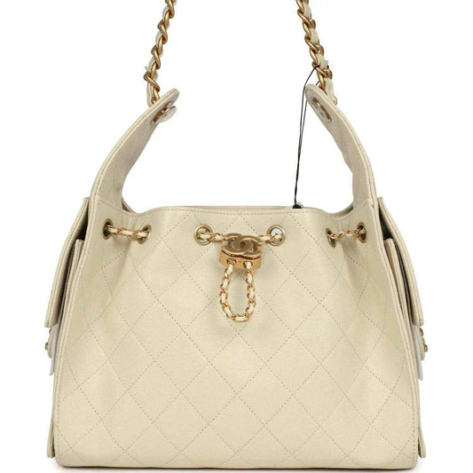 Light beige caviar hobo bag with gold-tone chain handles and front charm hardware