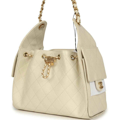 Light beige caviar hobo bag with gold-tone chain strap, quilted side panels, and tassel