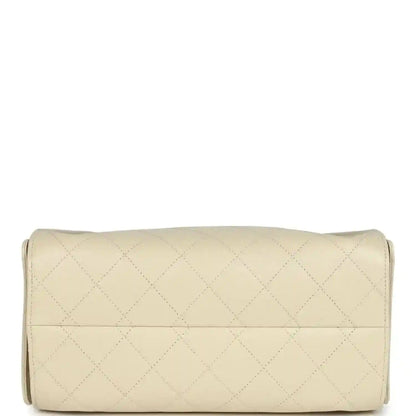 Light beige quilted hobo bag with cylindrical base and stitched seam across front