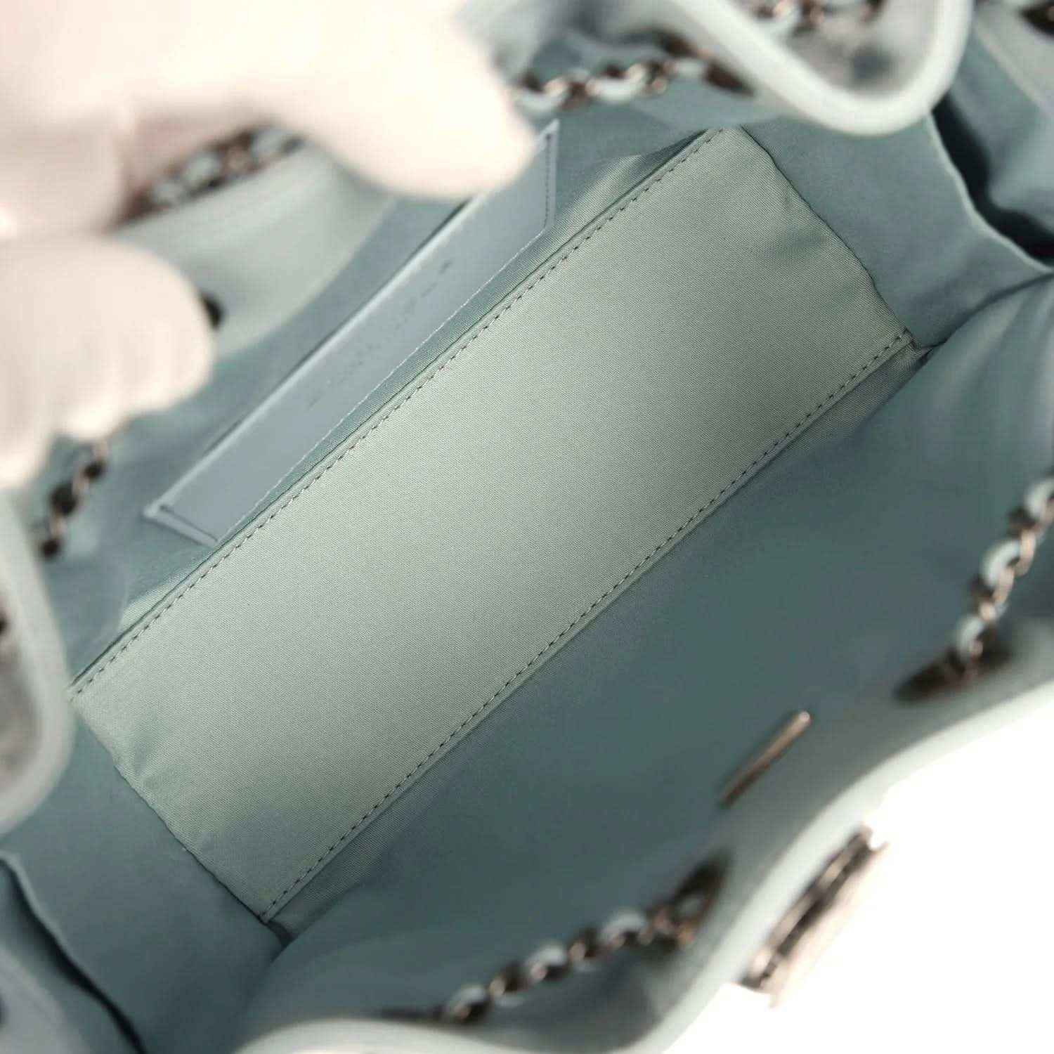 Light blue interior pocket panel with stitched seam and chain strap hardware