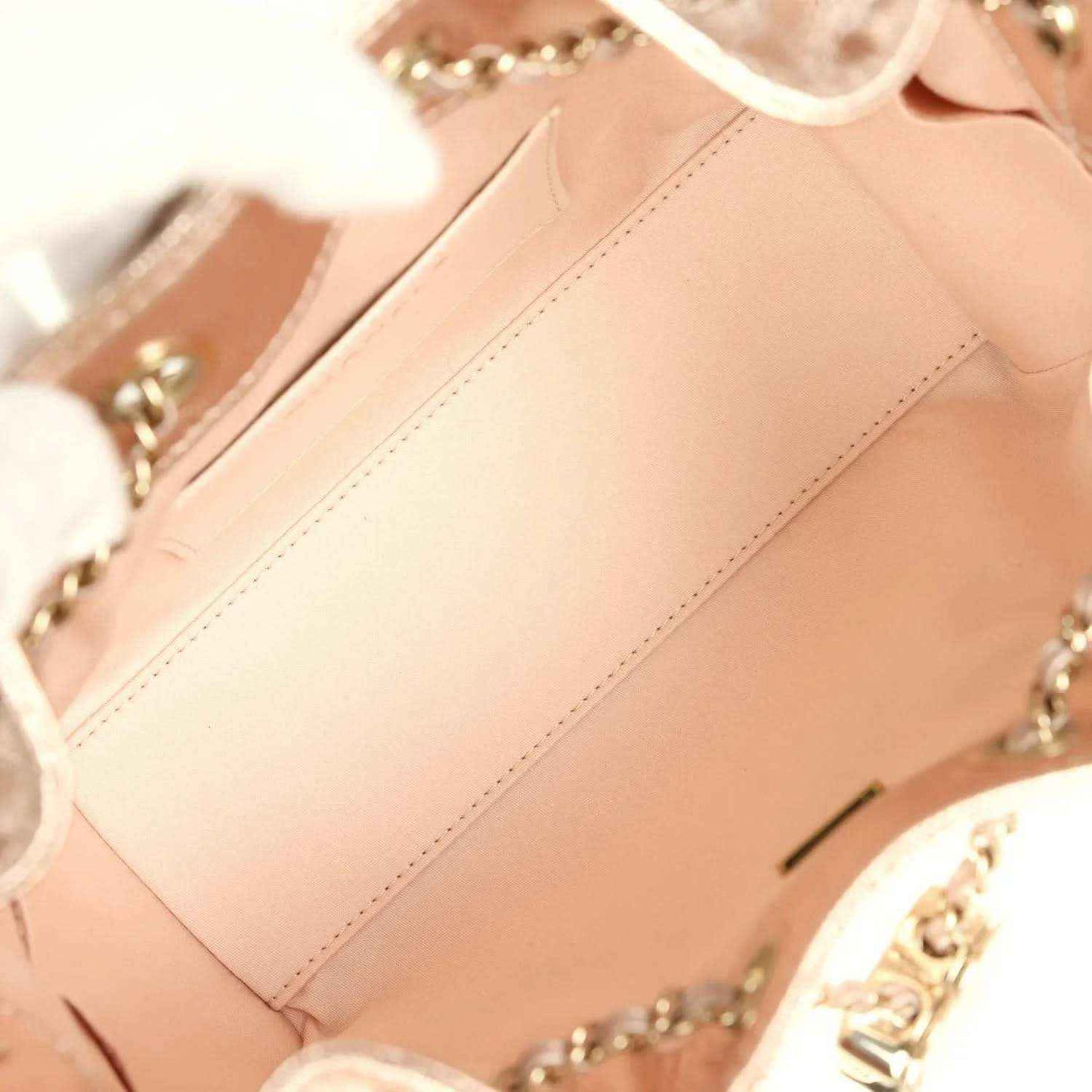 Metallic hobo bag interior lining and stitched seams with chain hardware visible, rose-gold