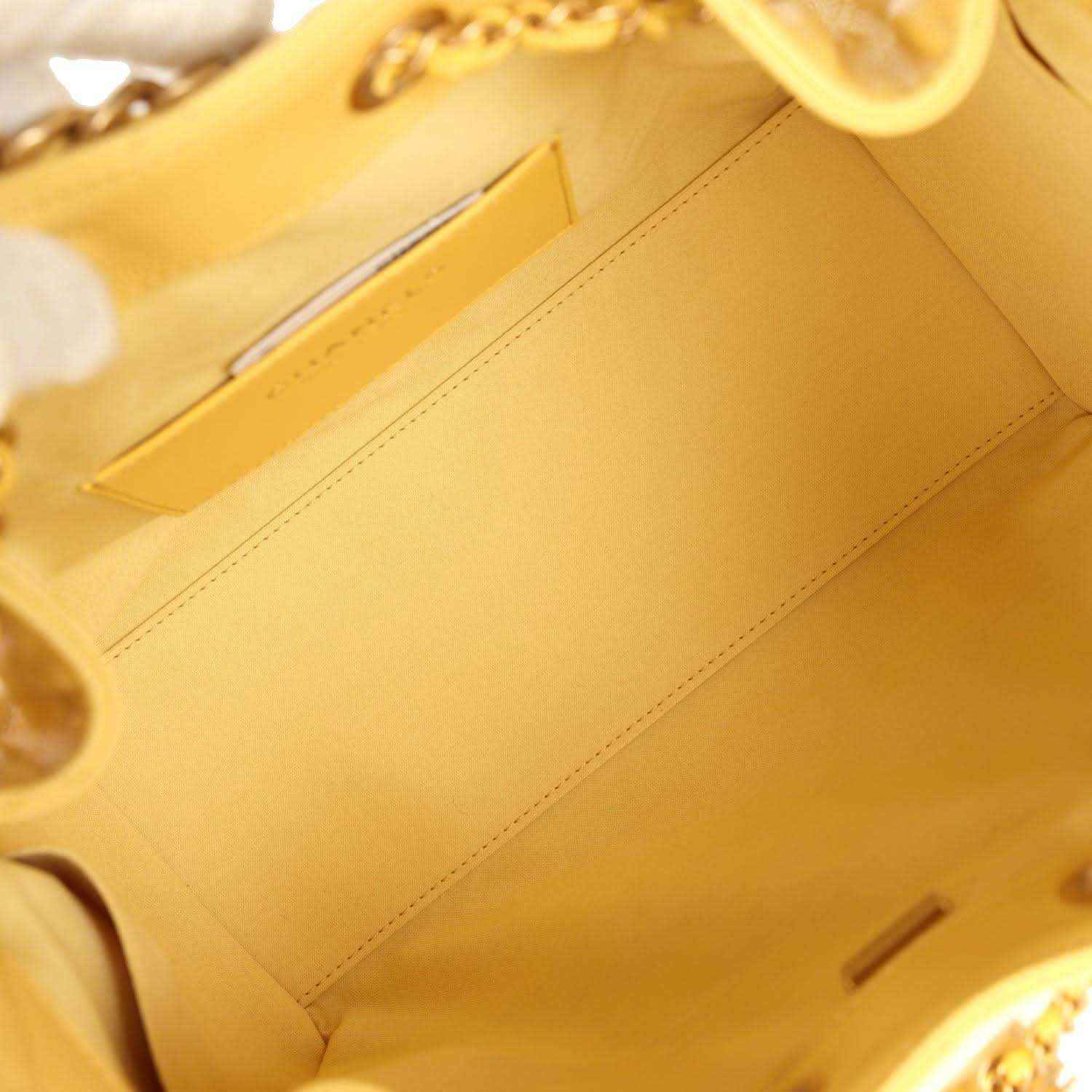Yellow fabric interior pocket of quilted hobo bag, visible stitching and tab