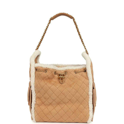 Beige quilted suede hobo bag with white shearling trim, gold chain handle and side tassels