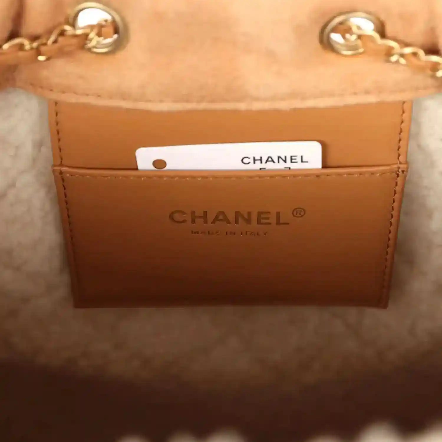Chanel hobo bag interior label with gold logo text and white tag on beige leather lining