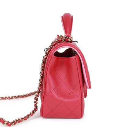 Pink quilted mini flap bag side view with chain strap and top handle.