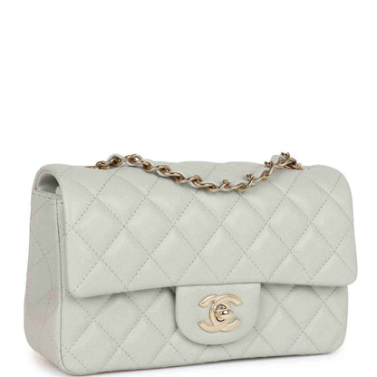 Light grey quilted mini flap bag with front logo emblem and gold-tone chain