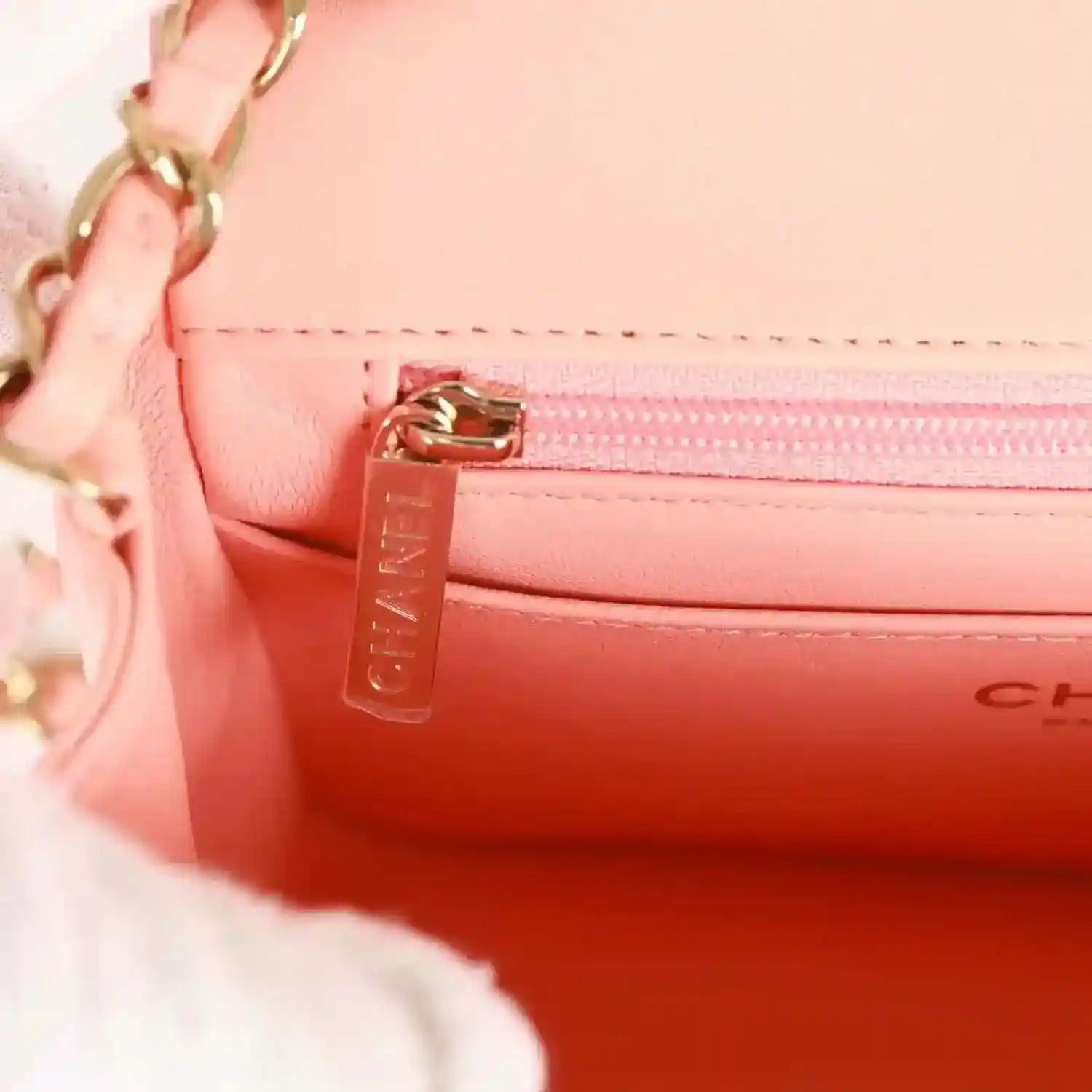 Mini flap bag interior with gold zipper pull and embossed “CHANEL” lettering
