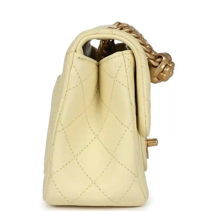 Mini quilted flap bag in pale yellow leather, side view with top handle opening and gold hardware