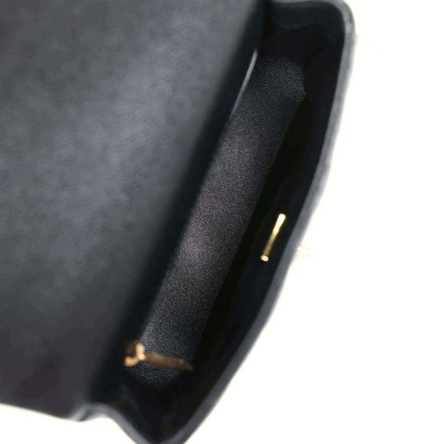 Black leather interior edge of mini flap bag with small gold-tone detail.